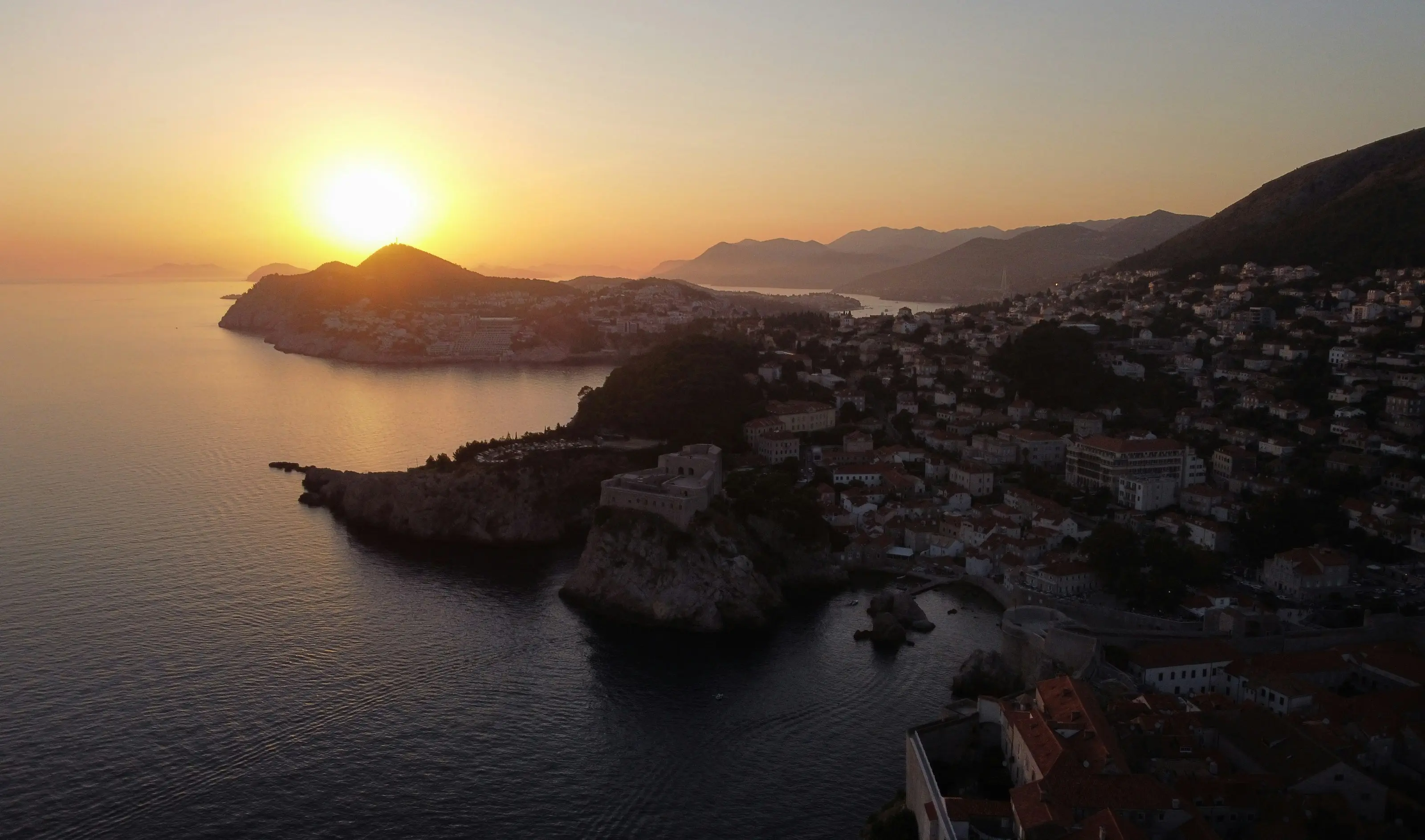 The sun is setting over a small town by the water
